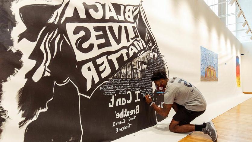 Student paints Black Lives Matter mural on wall at local art center